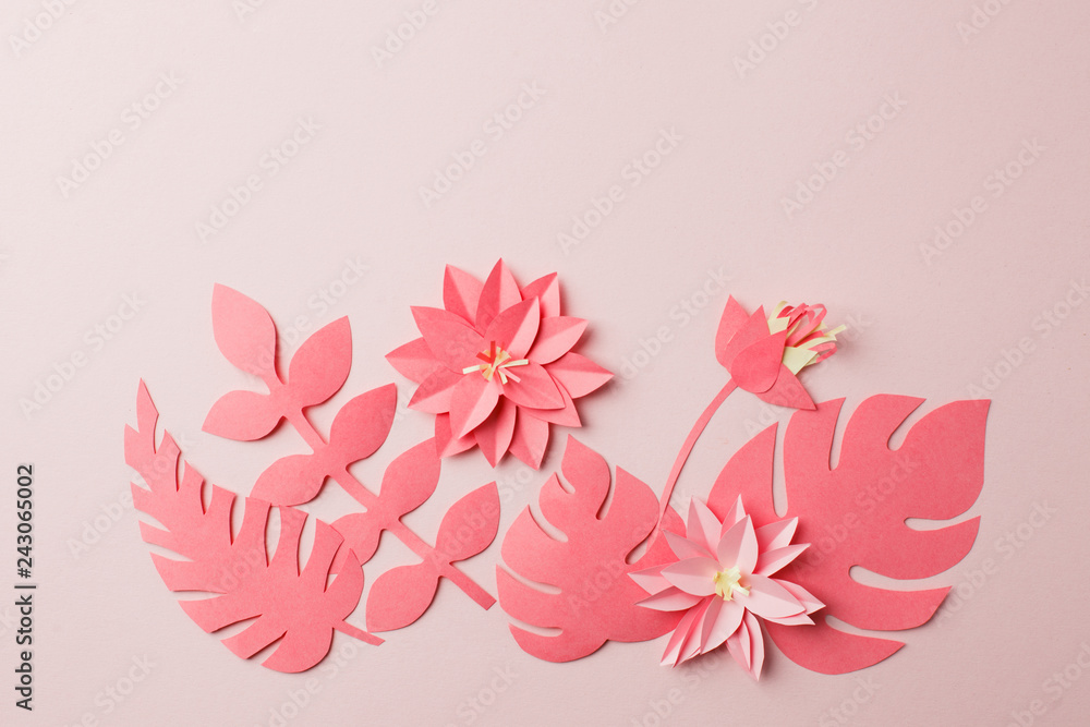 Fototapeta premium Handmade decorative paper pattern from tropical monochrome flower leaves on a pastel pink background with copy space. Top view. Live colar concept