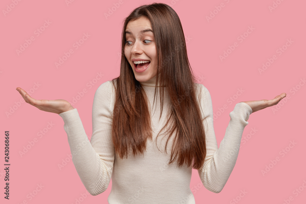 Happy Caucasian lady raises palms, feels hesitant and glad, chooses between two things, holds copy space, wears white outfit, isolated over pink background. So, what to choose now? Choice concept Happy Caucasian lady raises palms, feels hesitant and glad, chooses between two things, holds copy space, wears white outfit, isolated over pink background. So, what to choose now? Choice concept