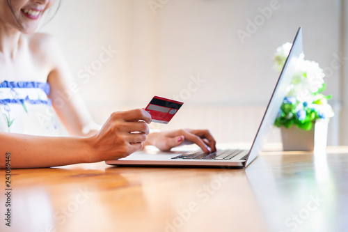 Happy asian woman wearing a sexy dress and buying online with a red credit card. Online Shopping Website on Laptop.
