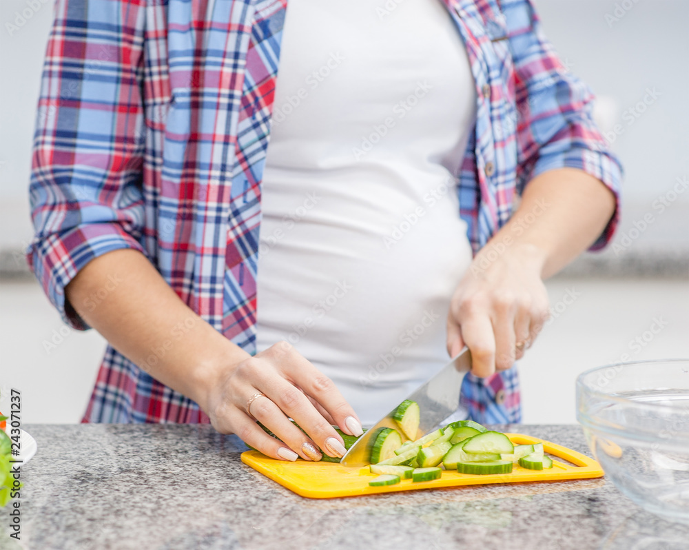 Close up pregnant woman preparing food at kitchen Close up pregnant woman preparing food at kitchen