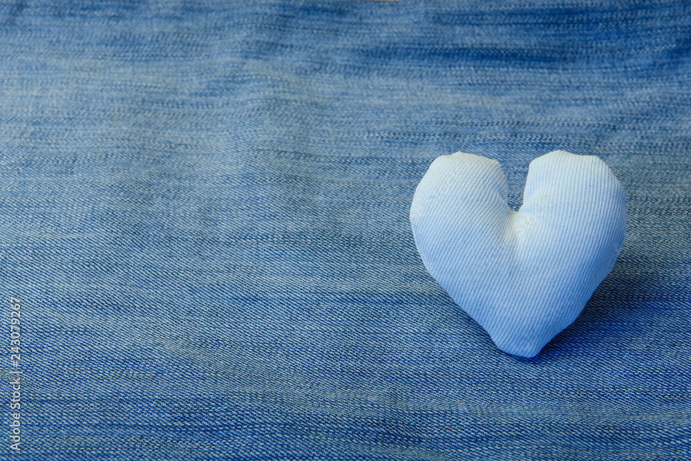 Fototapeta premium A white fabric heart lies on a denim background,