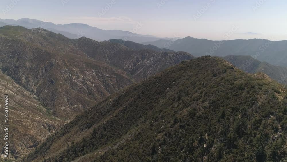 Slowly rising aerial shot i the California mountains, covered in trees and bushes. Rocky hills and clear skies, dramatic landscape. Slowly rising aerial shot i the California mountains, covered in trees and bushes. Rocky hills and clear skies, dramatic landscape.