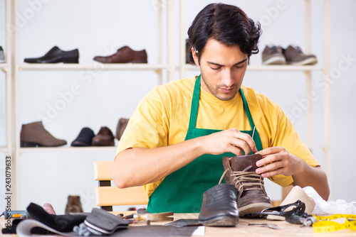 Young man repairing shoes in workshop 