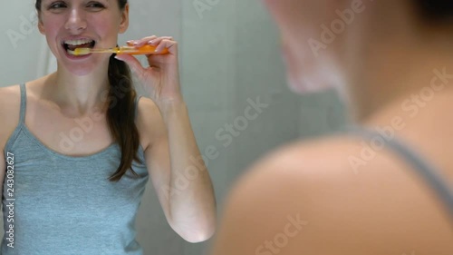 Pretty woman brushing her teeth in a bathroom in the morning. Morning hygiene. photo