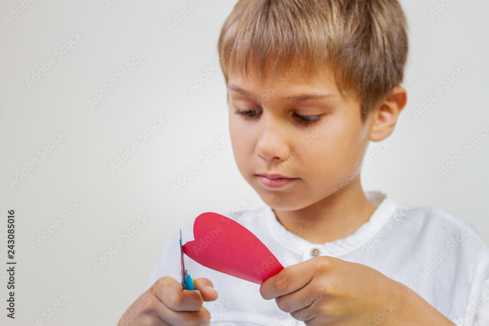 Child cutting red paper heart with scissors Child cutting red paper heart with scissors