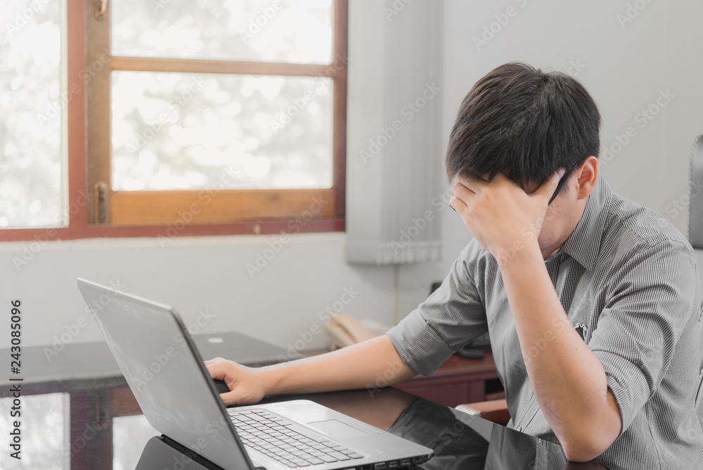 Businessman having stress with laptop computer working in the office,Exhausted asian man touching his head, he is having a bad headache, stress and overwork concept. Businessman having stress with laptop computer working in the office,Exhausted asian man touching his head, he is having a bad headache, stress and overwork concept.