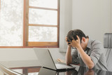 Businessman having stress with laptop computer working in the office,Exhausted asian man touching his head, he is having a bad headache, stress and overwork concept.