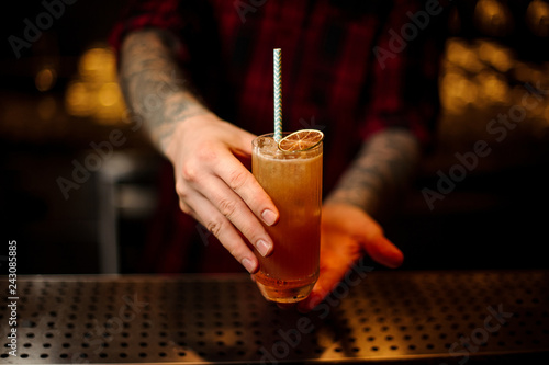 Bartender serving a Singapore Sling cocktail with orange zest