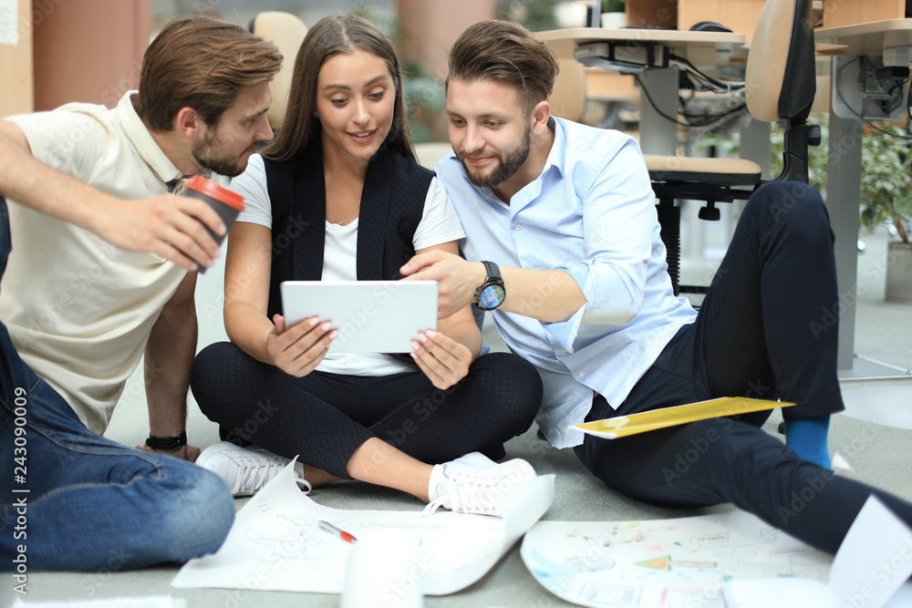 Fototapeta premium Group of young business people and designers looking at project plan laid out on floor. They working on new project.