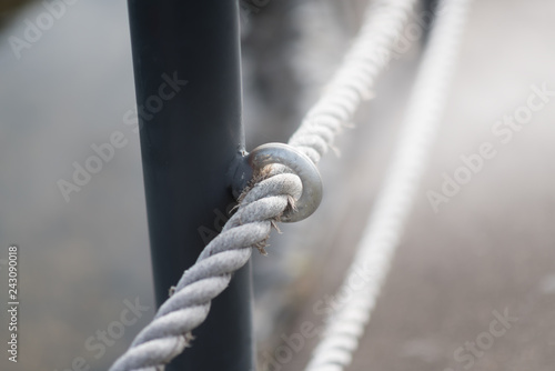 The white rope on the old metal fence.