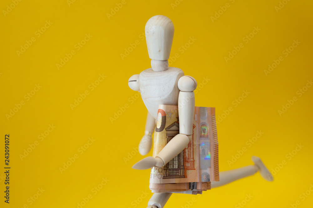 Wooden mannequiny running with a stack of banknotes. Economy.