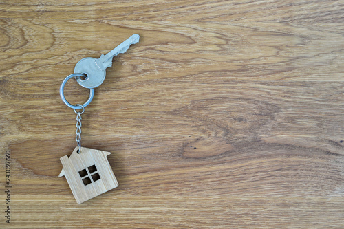 Metal house lock key in the form of bamboo keychain on wooden oak background. Copy space