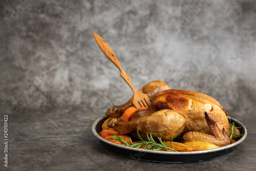 Roasted chicken, potatoes and vegetables in plate on grey background. Side view. With copy space