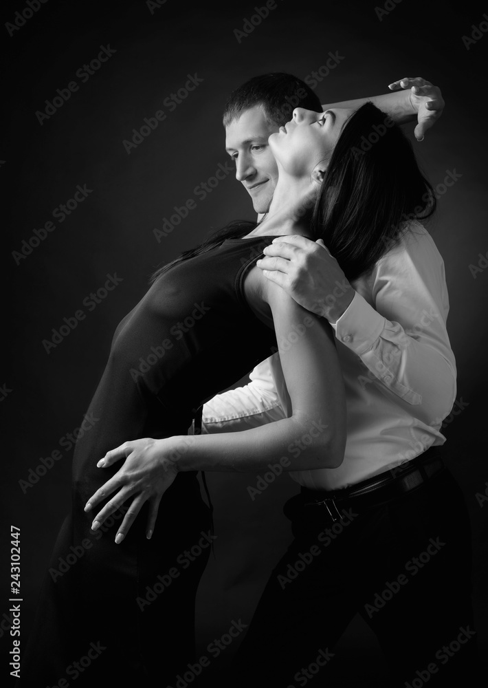 Young beautiful woman in black dress and man in white shirt dancing tango.