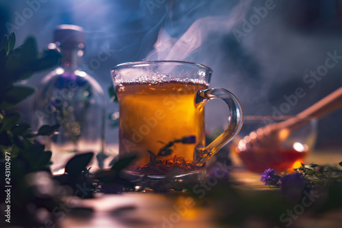Black tea in a transparent mug, violet flowers, beautiful dark b