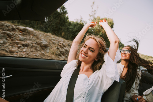 Young women driving in white cabriolet car and looking for freedom and fun
