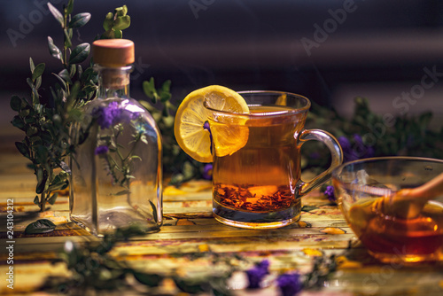 Black tea with lemon in a transparent mug, violet flowers, beaut