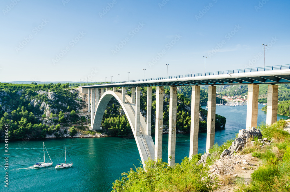 Small town of Skradin on Krka river, the entrance to the Krka National Park. Two yachts swimming into towns port under the big bridge.