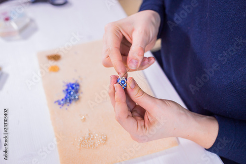 Professional jewelry designer making handmade eardrop with beads in studio, workshop. Fashion, creativity and handmade concept