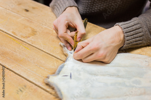 Professional male skinner, furrier working with mink fur skin at atelier, workshop. Fashion and leatherwork concept