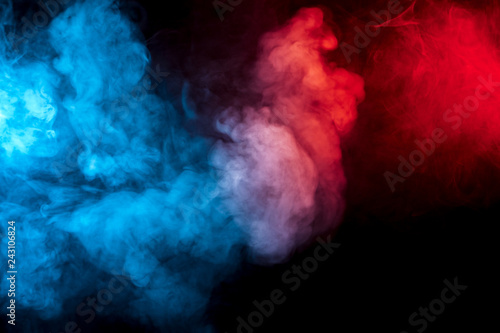 Clouds of isolated colored smoke: blue, red, orange, pink; scrolling on a black background in the dark close up.