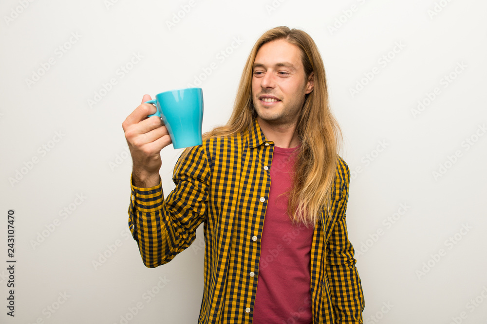 Blond man with long hair and with checkered shirt holding a hot cup of coffee Blond man with long hair and with checkered shirt holding a hot cup of coffee