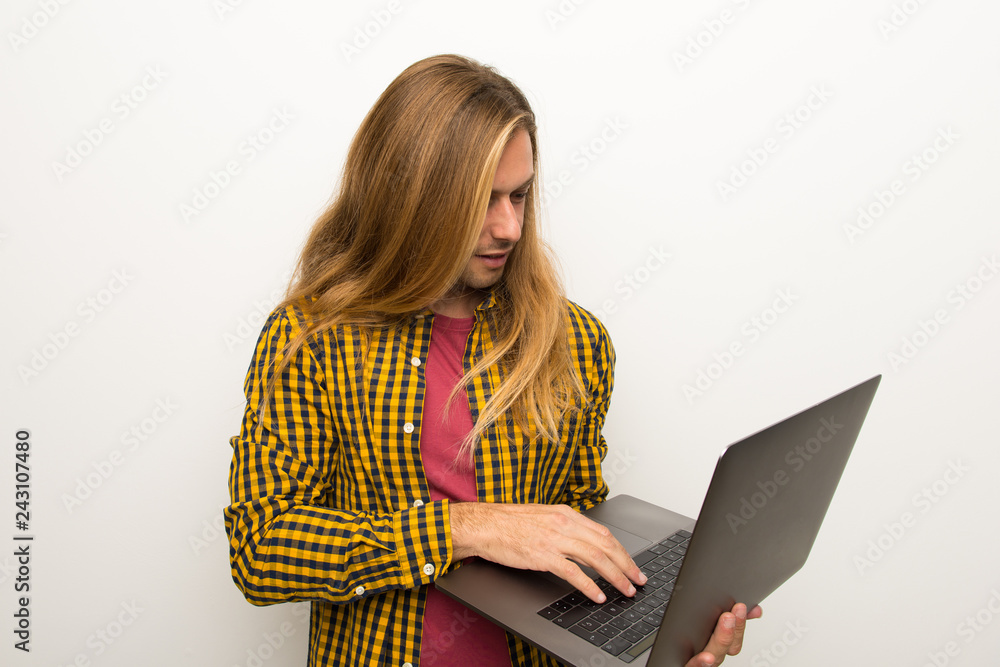 Naklejka premium Blond man with long hair and with checkered shirt with laptop