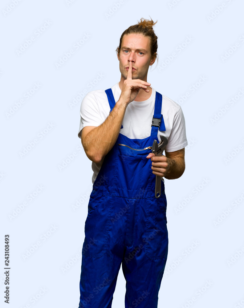 Workman showing a sign of silence gesture putting finger in mouth on isolated background Workman showing a sign of silence gesture putting finger in mouth on isolated background