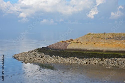 Various layers of mud, sand, gravel, rocks, baslat, tarmac, lichen and grass on a coastal dike between Oosterschelde estuary and the island of Noord-Beveland, The Netherlands on a hazy day photo