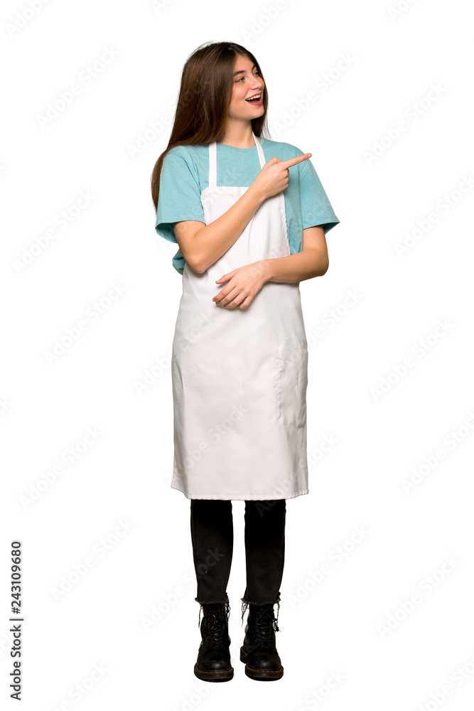 Full-length shot of Girl with apron pointing finger to the side in lateral position on isolated white background Full-length shot of Girl with apron pointing finger to the side in lateral position on isolated white background