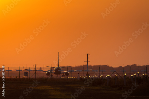 Plane on the track preparing to take off at sunset with red sky in background