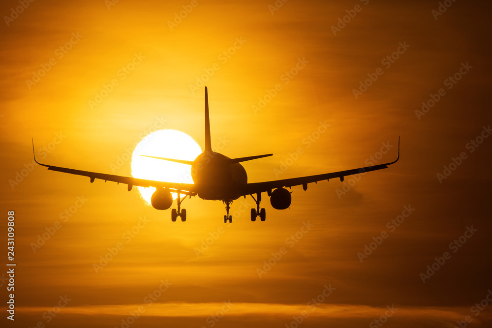 Silhouette of an air plane over the sun with beautiful red clouds in background Silhouette of an air plane over the sun with beautiful red clouds in background