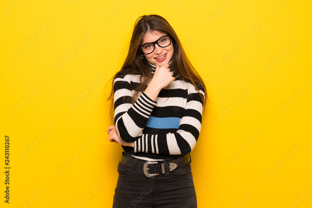 Young woman over yellow wall with glasses and smiling Young woman over yellow wall with glasses and smiling