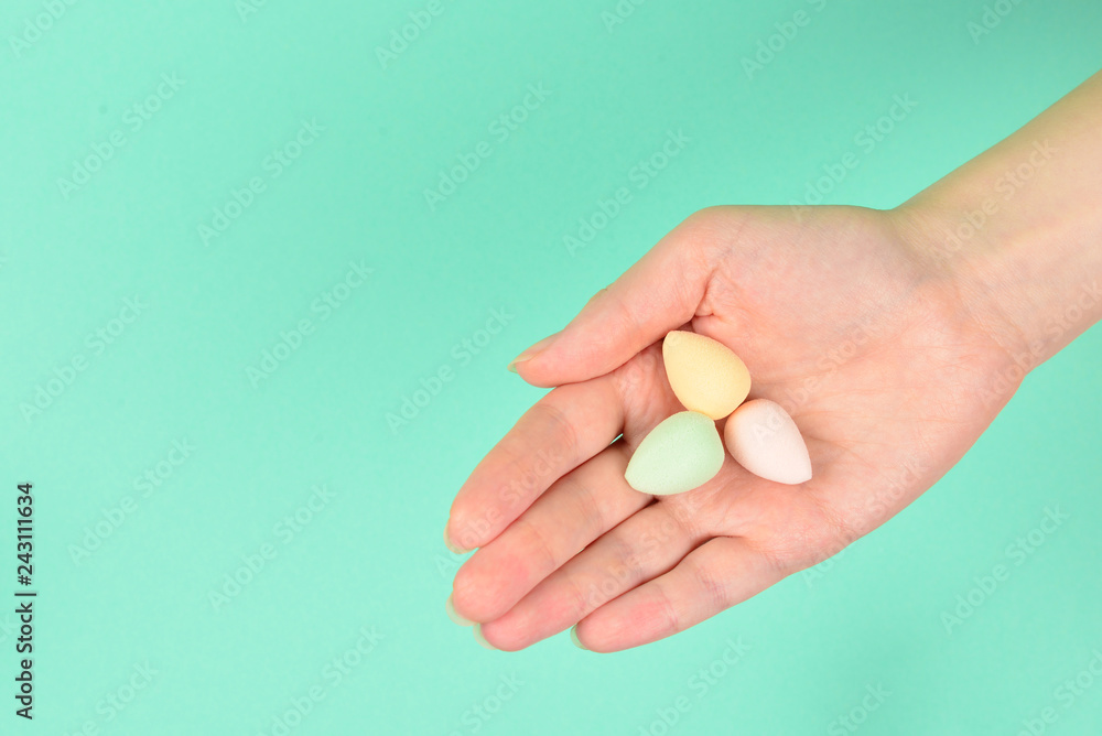 Woman hand holding beauty sponge on green background. Woman hand holding beauty sponge on green background.