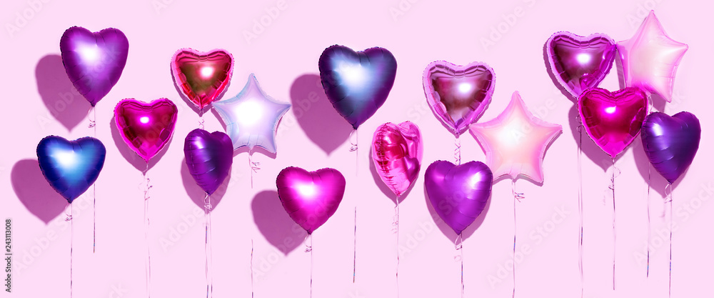 Air balloons. Bunch of purple heart shaped foil balloons, isolated on pink background. Valentine's day background. Wide screen