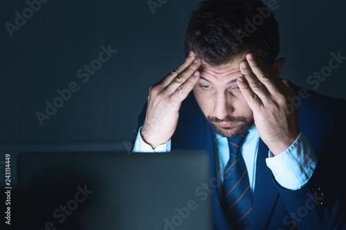 Stressed businessman using laptop working at night