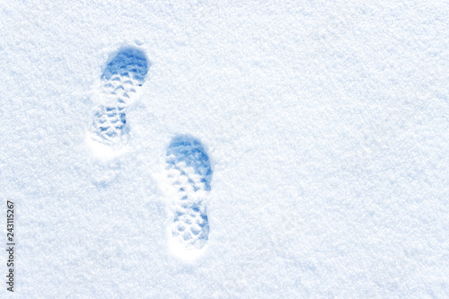 Footprints in deep snow and a tree on horizon. Winter landscape