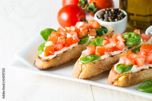 Tomato and cheese fresh made bruschetta. Italian tapas, antipasti with vegetables, herbs and oil on grilled ciabatta and baguette bread. Sandwich.