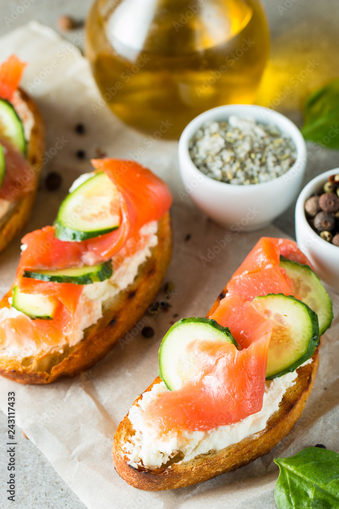 Salmon, cucumber and cream cheese bruschetta. Italian tapas, antipasti with vegetables, herbs and oil on grilled ciabatta and baguette bread. Sandwich.