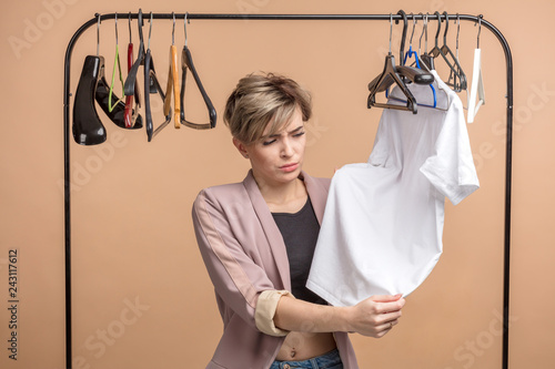 angry girl has found a black spot in the white T-shirt in the wordrobe . close up shot. photo