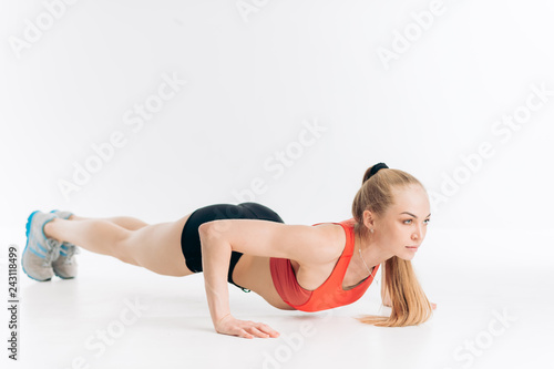 blond slim girl is performing press-ups full length side view shot.lifrstyle, health and body care photo