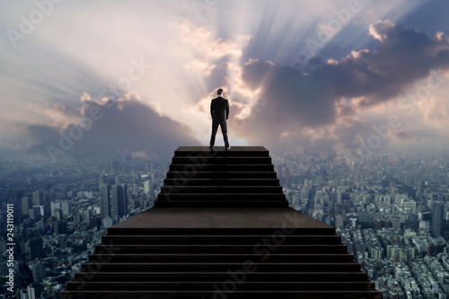 Success and leader concept, businessman in suit standing on top of stair and looking over city with sun light photo