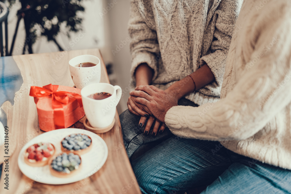 Couple sitting behind wooden table in cafe and holding by hands Couple sitting behind wooden table in cafe and holding by hands