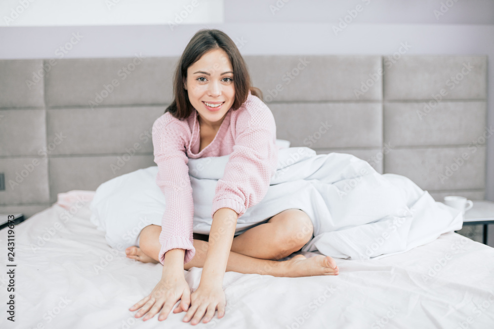 Positive smiling woman is sitting on the bed in modern room. beauty, leisure time Positive smiling woman is sitting on the bed in modern room. beauty, leisure time