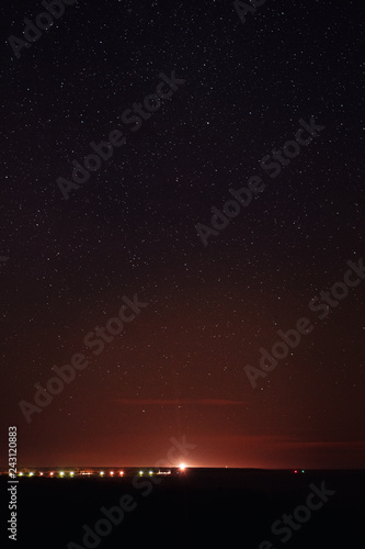 Night glow of the city zingst seen from the beach at night with stars sky. German Baltic Sea Darßer Ort, Weststrand coastline at Fischland-Darss-Zingst