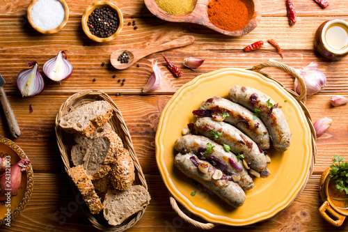 Raw white sausage on a wooden background with spices.