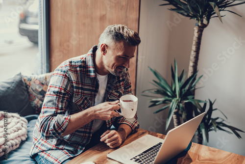 Cheerful man sitting with cup of tea in cafe photo