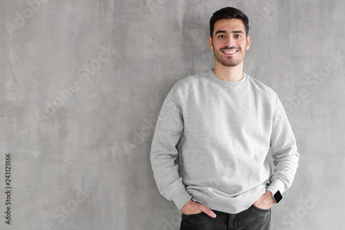 Photos Young man in oversized sweatshirt isolated on textured gray wall background with