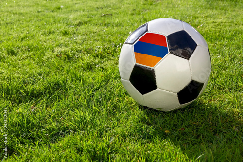 Football on a grass pitch with Armenia Flag