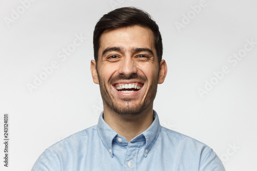 Portrait of handsome laughing business man, isolated on gray background